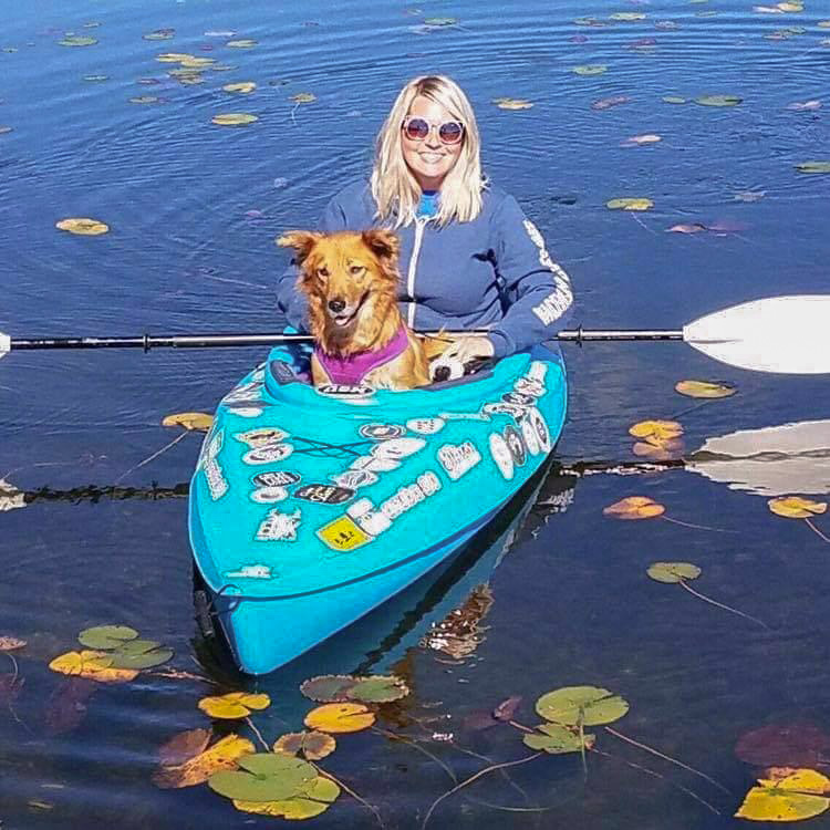 A woman and her Golden Retriever mix in a kayak.